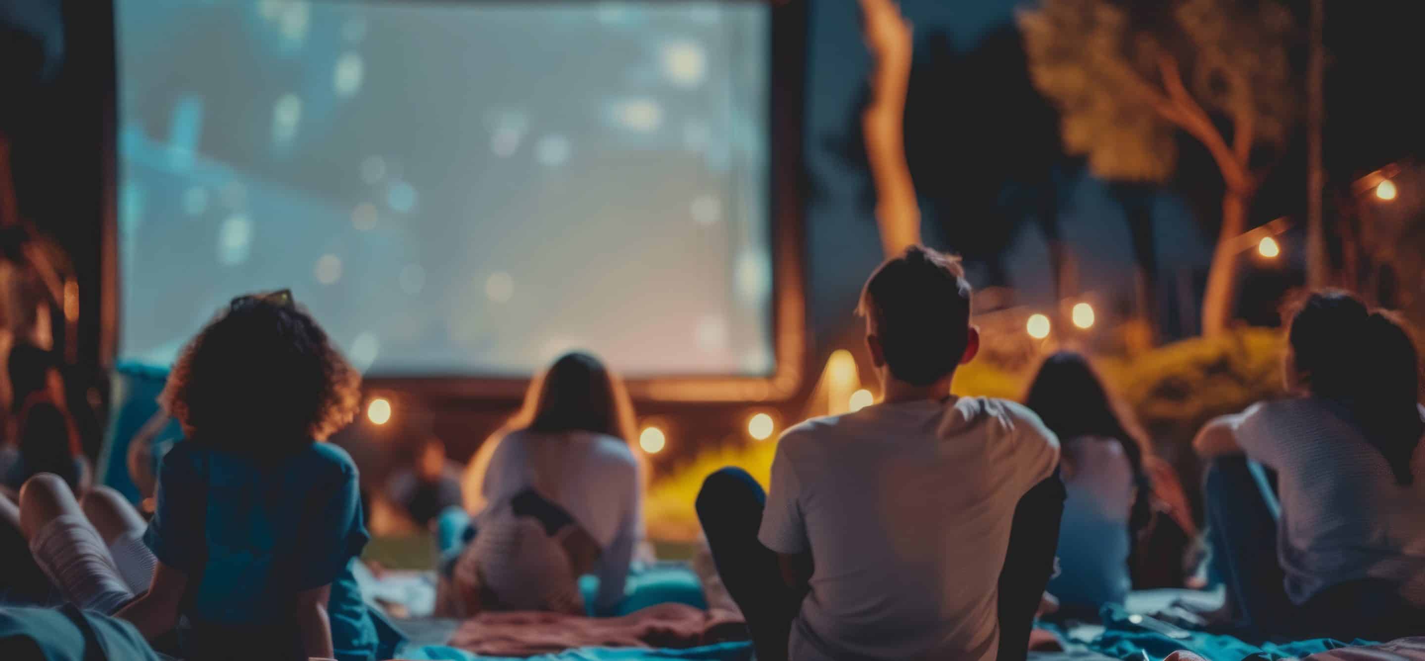 Group of people enjoying an outdoor movie night under the stars.